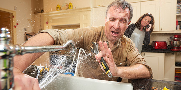 homeowner trying to fix broke kitchen pipes and water splashing everywhere
