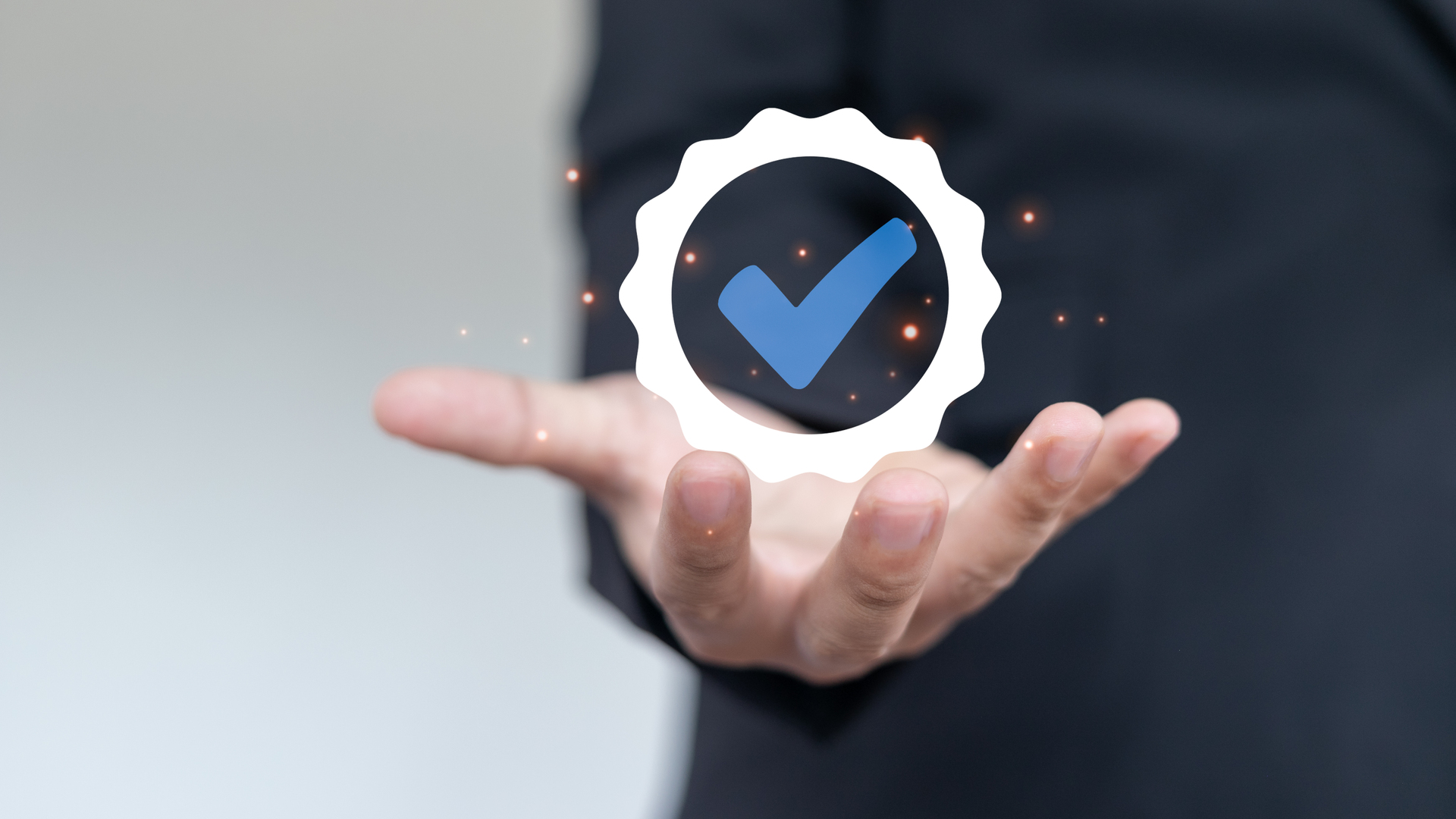Businessman showing verified check mark badge icon for quality assurance, certification, approval, and business guarantee concept on virtual screen.