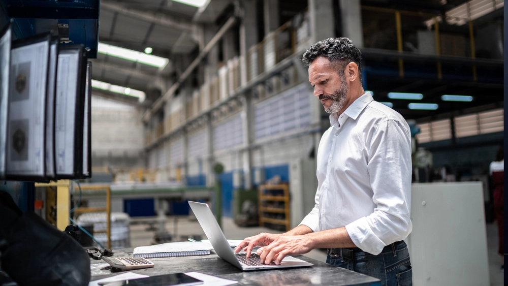 Stock image of man looking at laptop in warehouse
