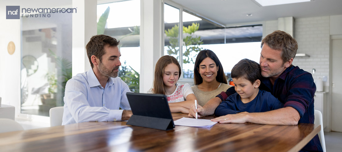 A white family sits smiling around a laptop