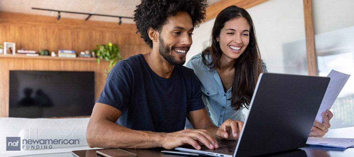 couple laughing to a laptop