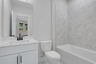 secondary bathroom with white cabinets and tile flooring