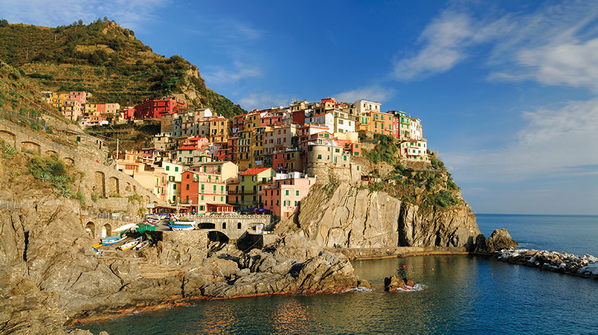 Colorful houses are built into the rocky cliffs of Cinque Terre, Italy, overlooking the calm blue sea.
