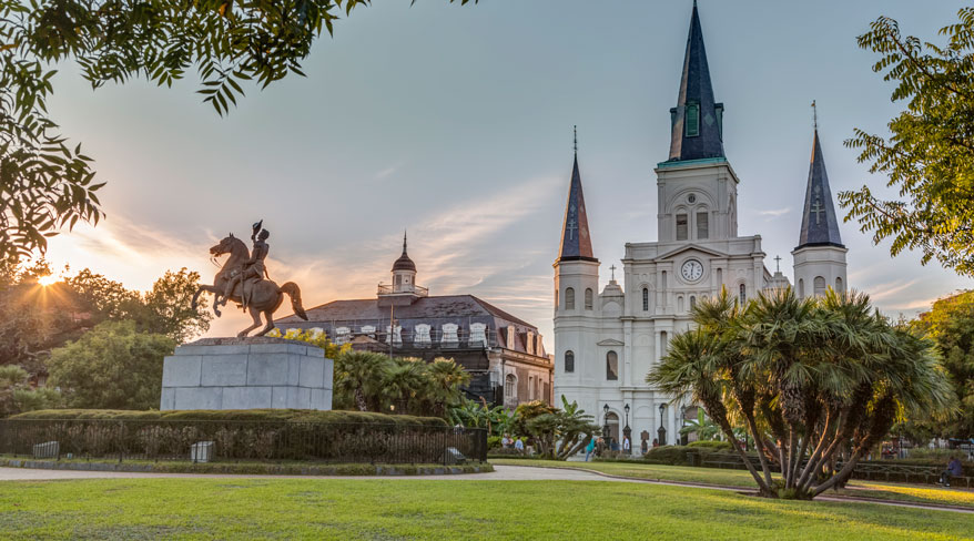 A photo of St. Louis Cathedral and the Andrew Jackson statue in Jackson Square, New Orleans, at sunset.
