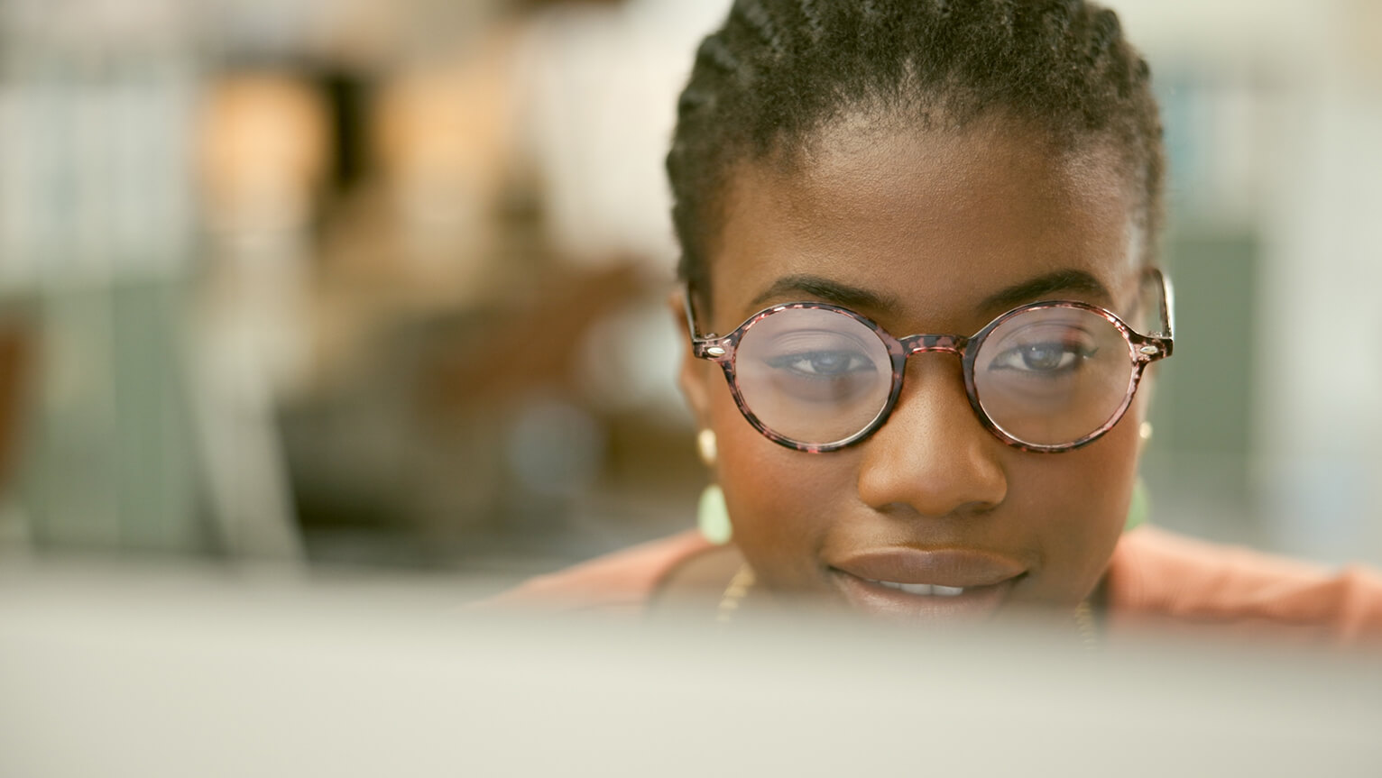 Woman wearing glasses looking at monitor.