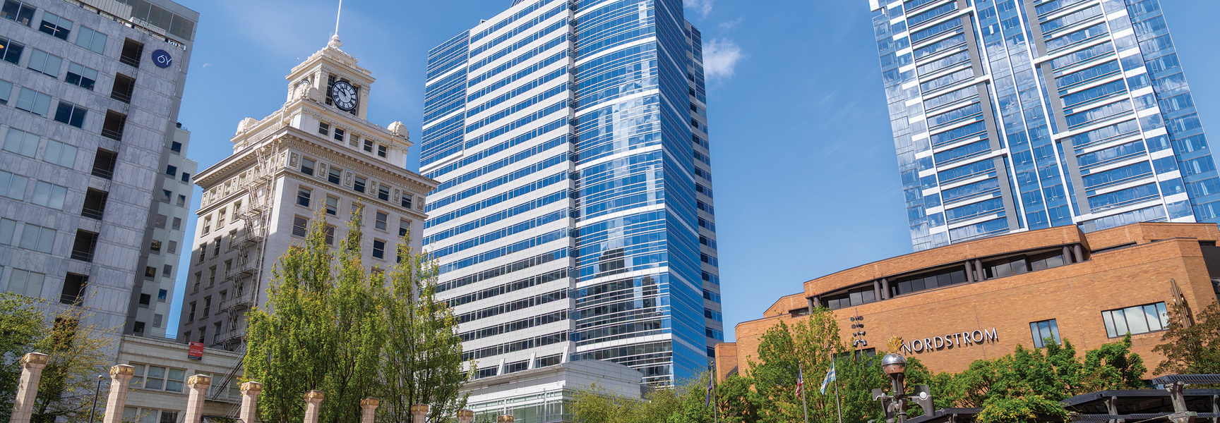 A view looking up at modern and historic buildings against a blue sky in downtown Portland, Oregon.