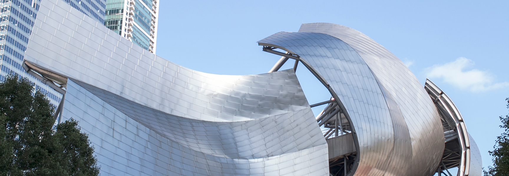A low-angle shot of the Jay Pritzker Pavilion's sculptural metal ribbons against a blue sky in Chicago, Illinois.