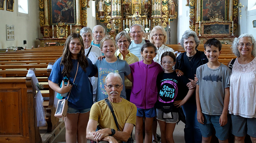A group of grandparents and grandchildren smile for a photo inside the ornate Maria in der Tanne church in Triberg, Germany.