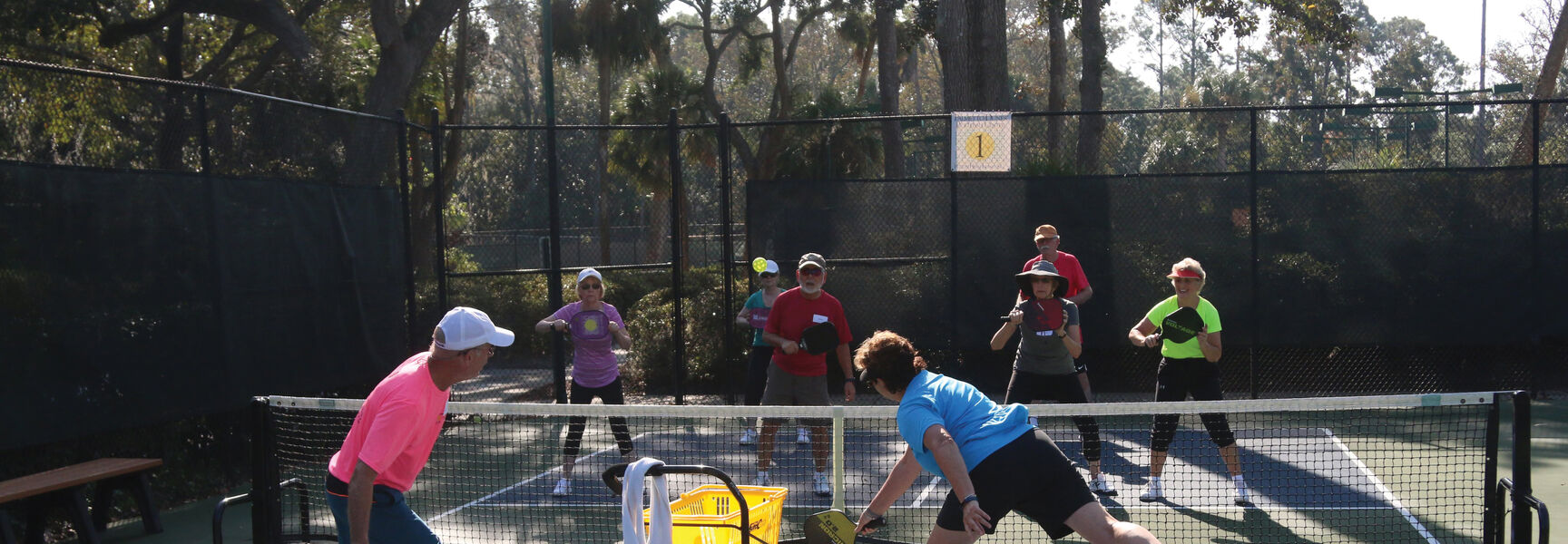 Road Scholars practice pickleball skills with instructors on a sunny outdoor court at Glen Sutton Lodge in Québec.