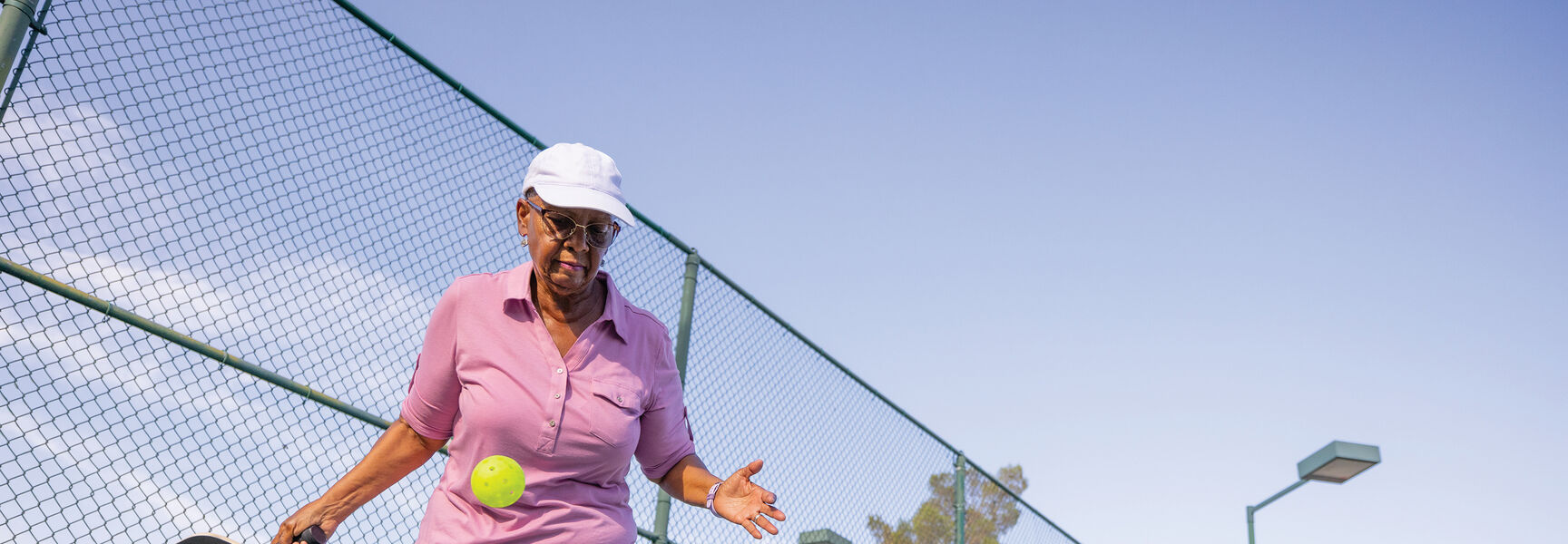 An older woman practices pickleball skills on an outdoor court at a state-of-the-art facility in Washington, located in the Pacific Northwest.