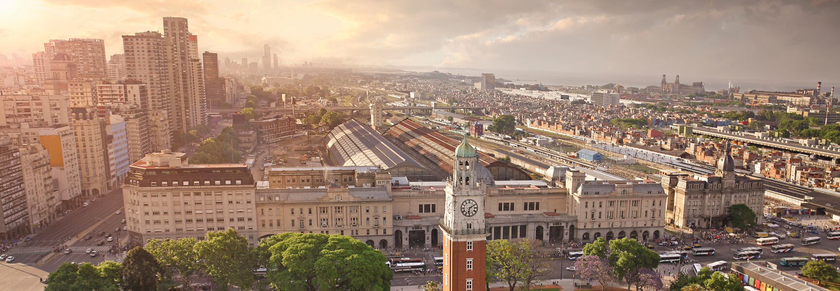 An aerial view of the Torre Monumental clock tower in a lush green park surrounded by the urban cityscape of Buenos Aires, Argentina.