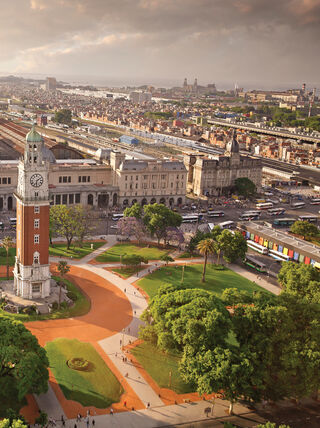 An aerial view of the Torre Monumental clock tower in a lush green park surrounded by the urban cityscape of Buenos Aires, Argentina.