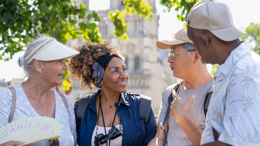 A diverse group of seniors engaging in prosocial behavior and the psychology of kindness while conversing outdoors near a historic cathedral.
