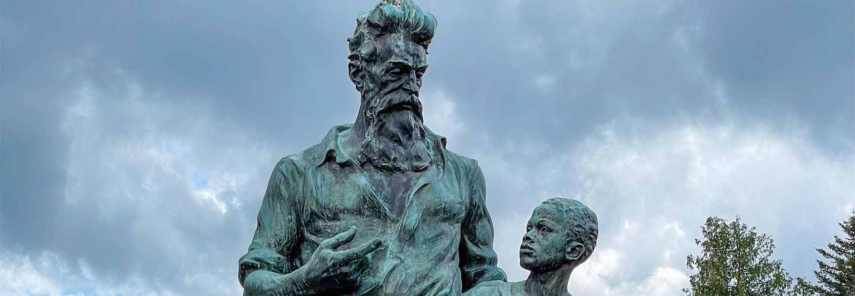 Bronze statue of abolitionist John Brown standing with a young child under a cloudy sky, symbolizing the 1850s Road to the Civil War.
