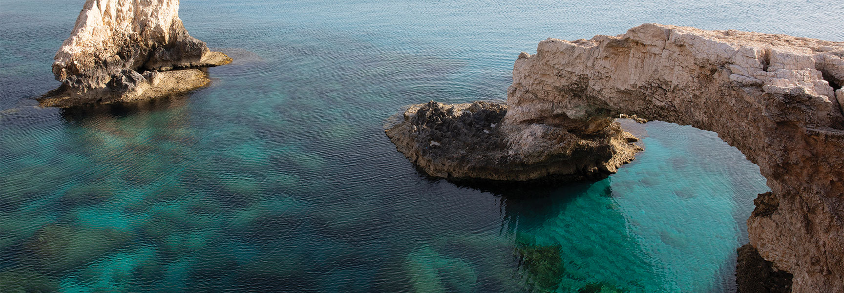 Rocky sea arch and clear turquoise water representing the islands and coastal geography of Odysseus’ voyage from Homer’s Odyssey.