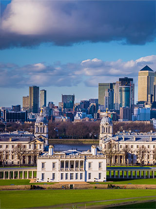 The historic National Maritime Museum in England, with the modern skyscrapers of the London skyline rising in the background.