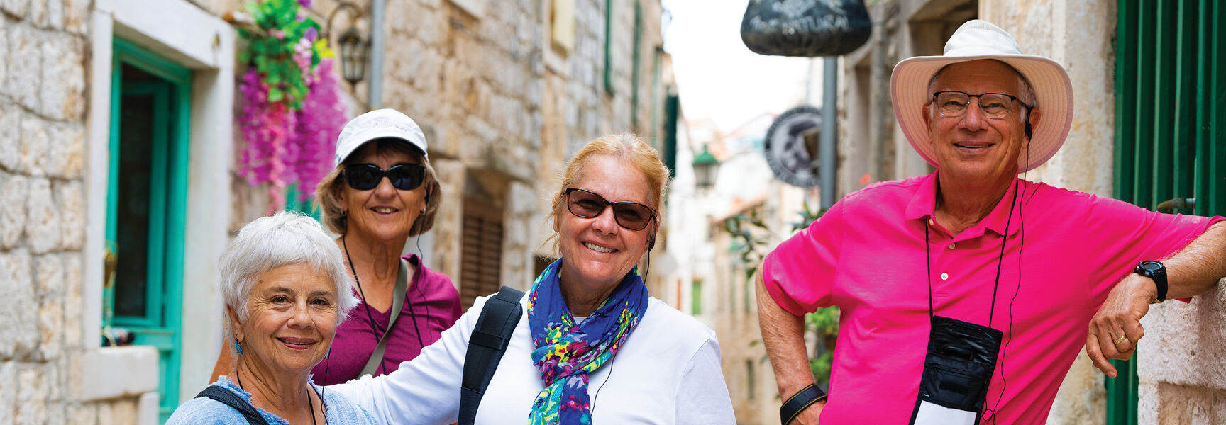 Four smiling senior travelers pose in a narrow, sunlit stone alleyway during a Voyage Through History tour of the Adriatic.