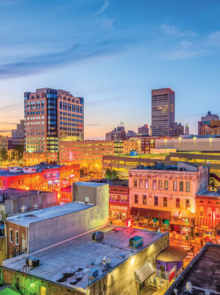 Vibrant sunset cityscape of Memphis featuring neon lights and historic buildings, reflecting the history of the Civil Rights Movement in Southern cities like Jackson.