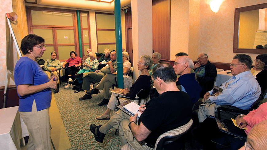 An instructor leads a presentation for a group of adults in a Bordeaux classroom while students listen and take notes.