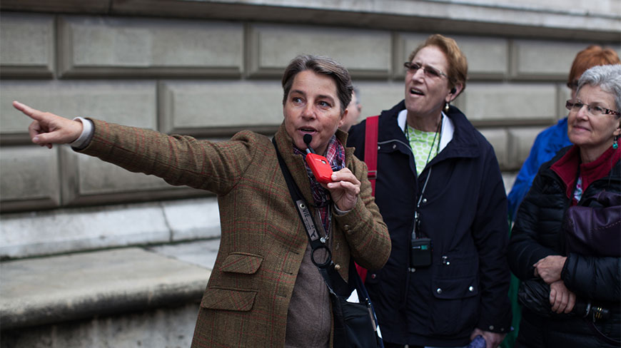 Vienna guide Gabriella points out sights while speaking into a microphone for a group of tourists.