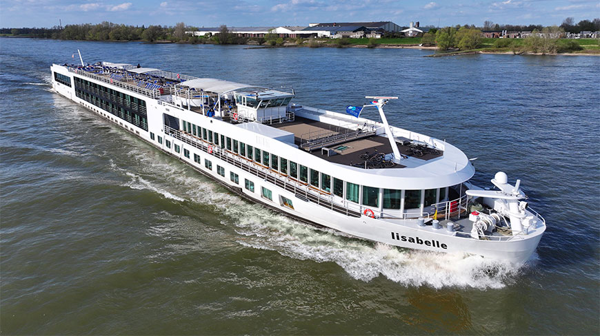The white RadReisen river cruise ship MS Lisabelle cruises along a wide river with green banks and distant buildings under a clear sky.