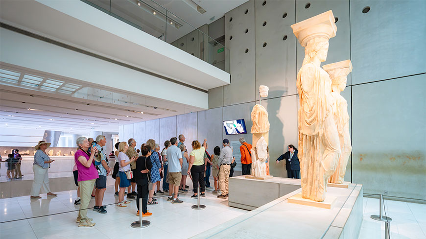 Visitors look at ancient Caryatid statues on display inside the modern Acropolis Museum in Athens.
