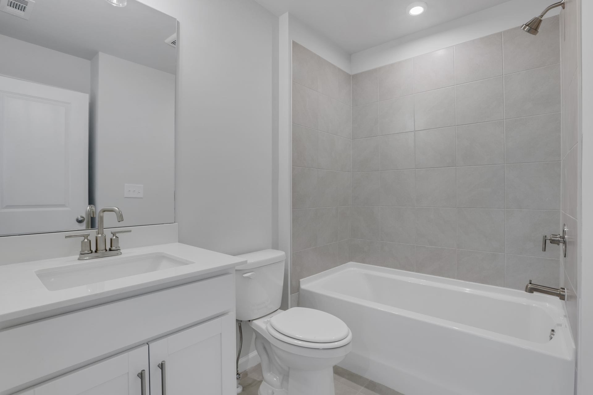 secondary bathroom with white cabinets and tile flooring