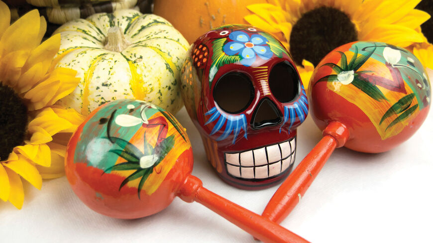A colorful sugar skull and hand-painted maracas among sunflowers and pumpkins for a Día de Los Muertos celebration in Oaxaca, Mexico.
