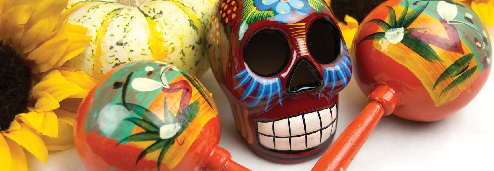 A colorful sugar skull and hand-painted maracas among sunflowers and pumpkins for a Día de Los Muertos celebration in Oaxaca, Mexico.