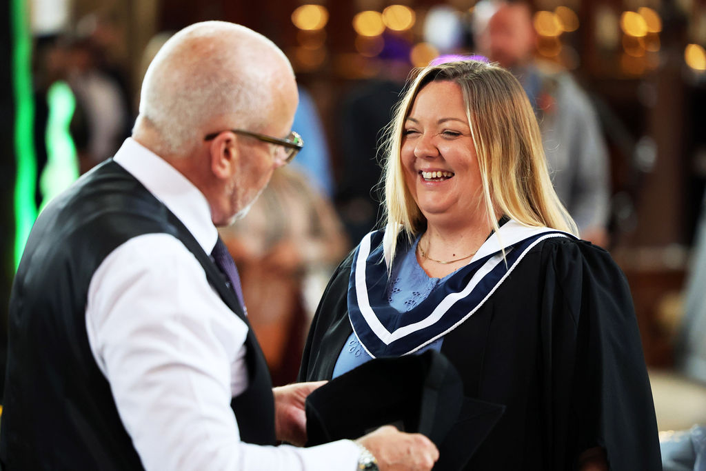 A graduate smiling warmly while speaking with a man holding a mortarboard