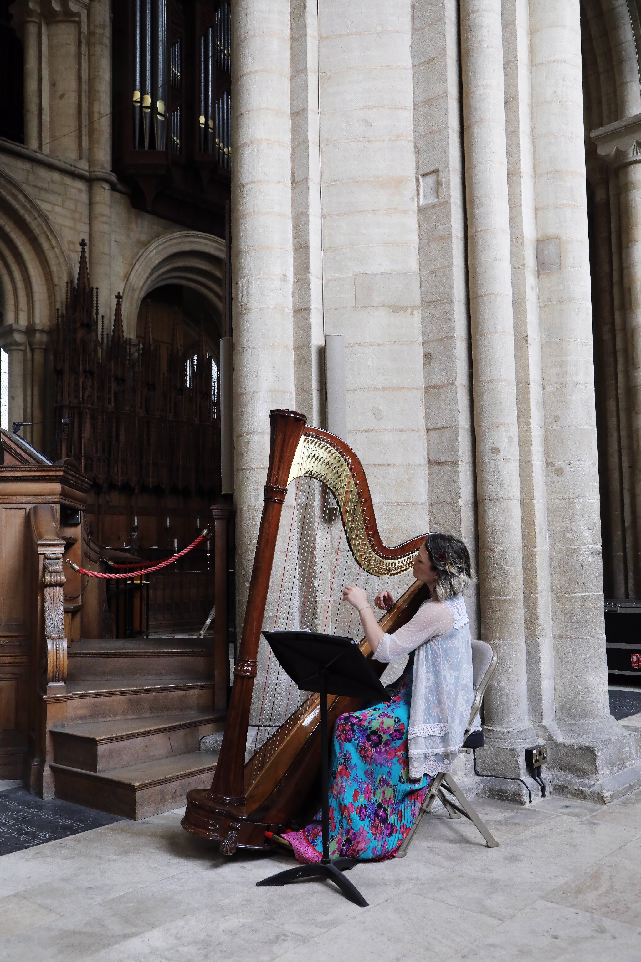 A woman playing a large wooden harp inside a cathedral