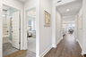 entryway with hardwood floor, white walls, bathroom and bedroom off of hallway