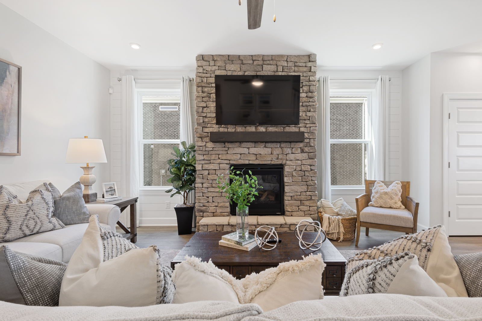 great room with wood floors, large windows, and stone fireplace