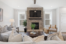 great room with wood floors, large windows, and stone fireplace