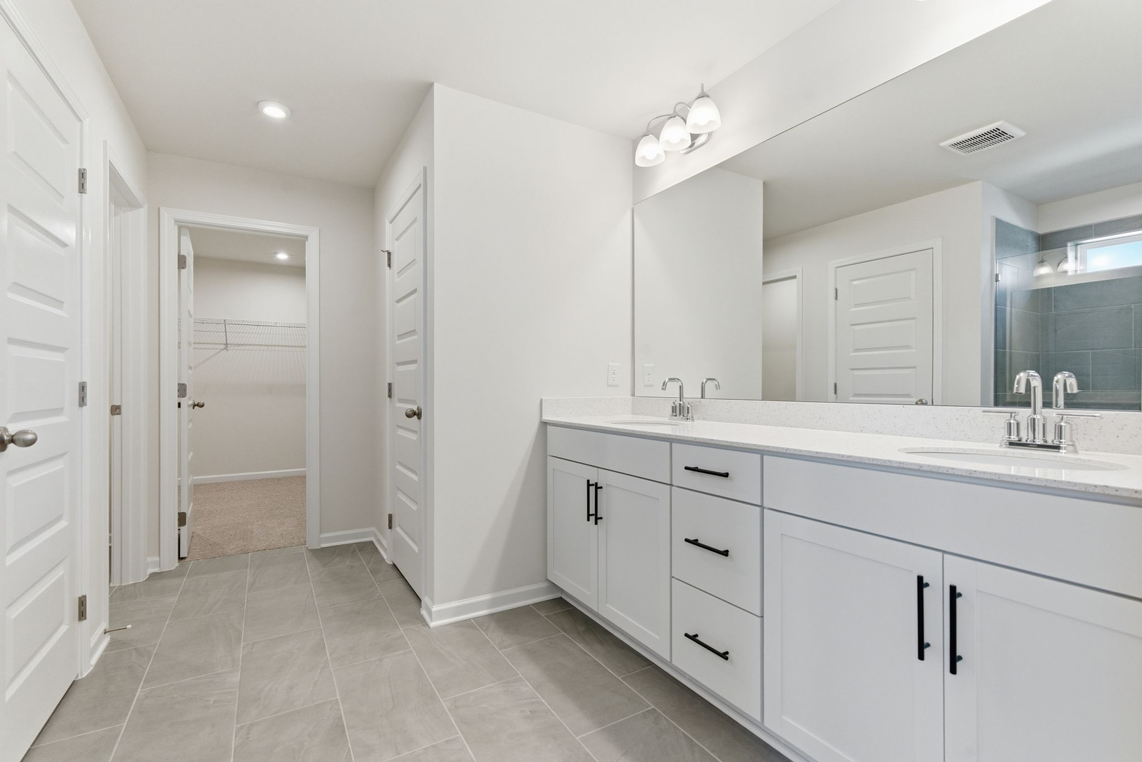 primary bathroom with dual vanity sinks and white cabinetry