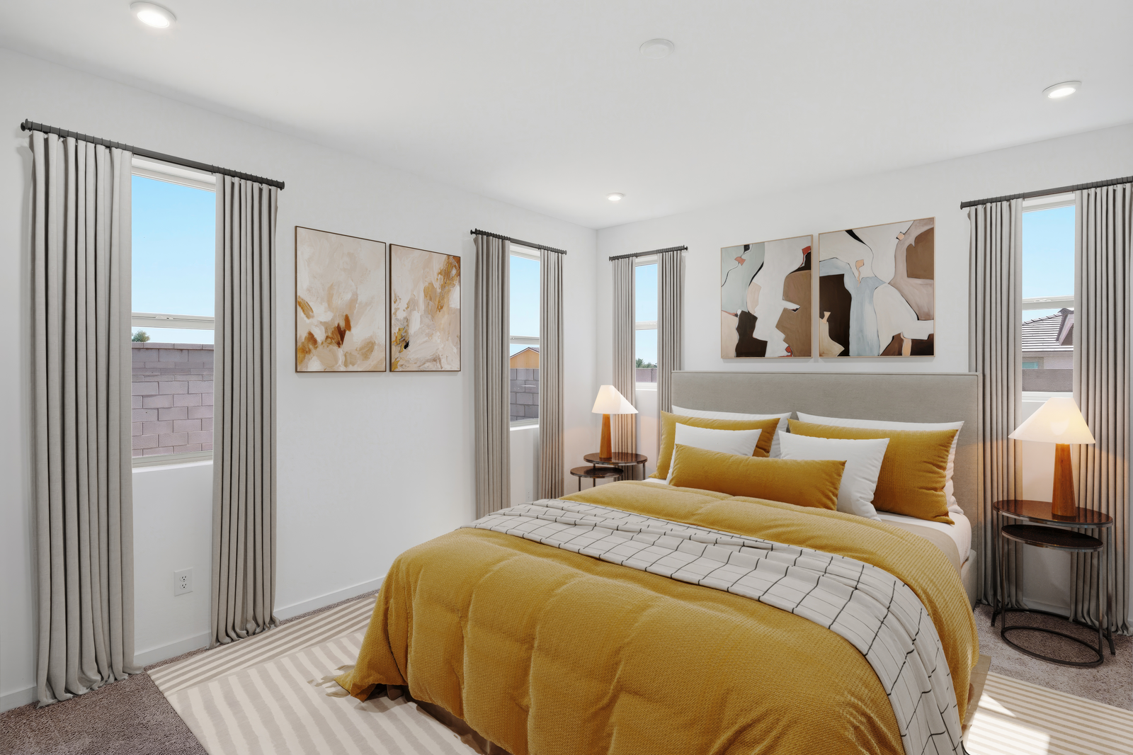 spacious bedroom with a king-sized bed with yellow bed covers, a white rug, and white accent pillows