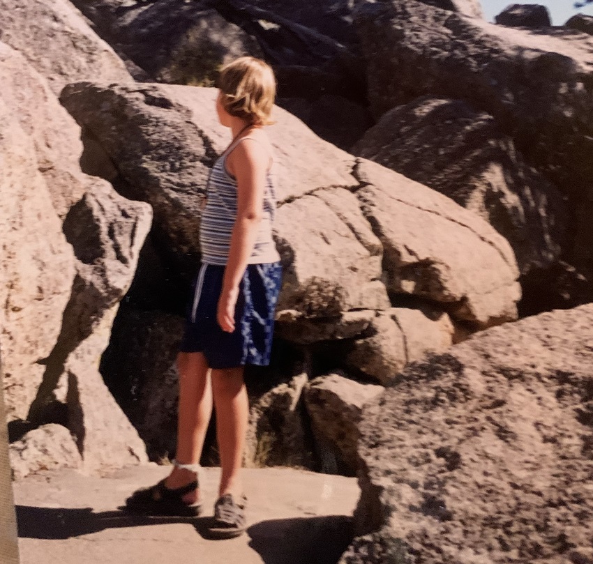 Beckah faces away from the camera towards rocks in the background