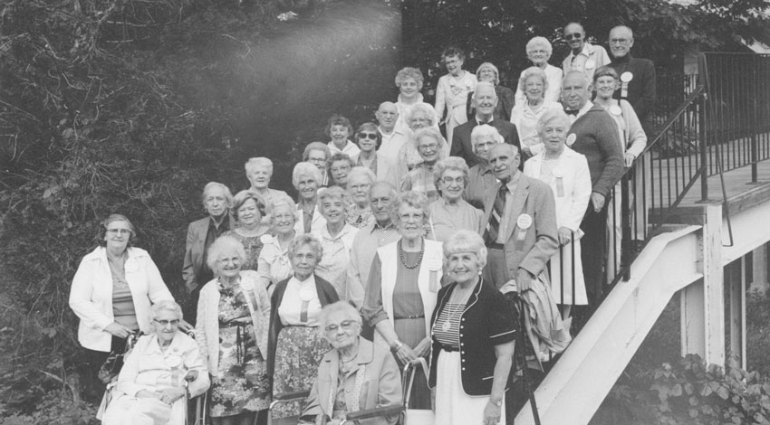 A black and white photograph of Jim Verschueren's group, featuring numerous senior citizens posing together outdoors on a staircase.