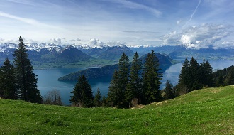 A panoramic view of Swiss meadows, lakes and mountains