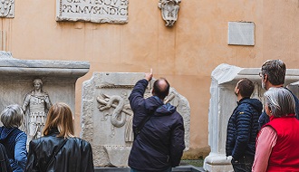 An instructor points at artifacts, while participants look on