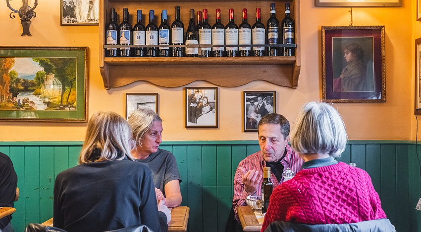 Four people sit at small tables and engage in discussion