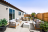 backyard with large concrete patio, gray outdoor furniture, and multiple potted plants
