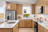 kitchen with light wood cabinets & floors, white counters, window, and island