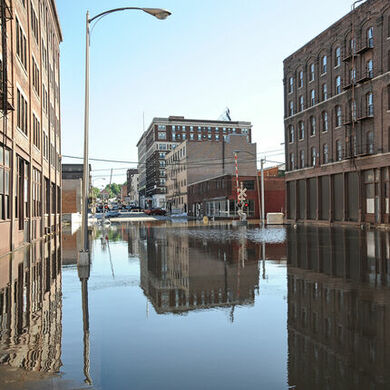 Flooded main street between multi-story, industrial brick buildings