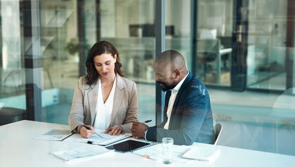 Co-workers sitting at a table looking over financial documents