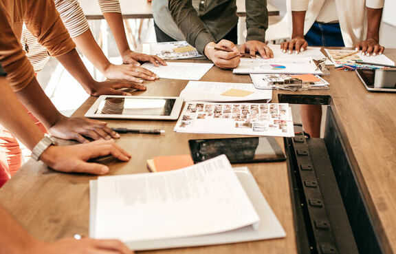 Business people gathered in a meeting room with their hands down on the table