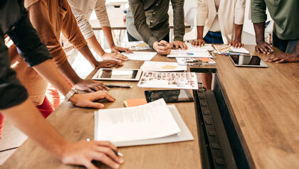 Business people gathered in a meeting room with their hands down on the table