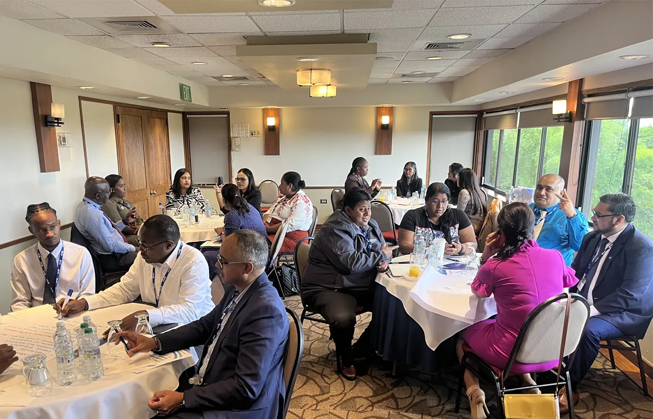 A room full of people sitting around circular tables, networking and discussing.