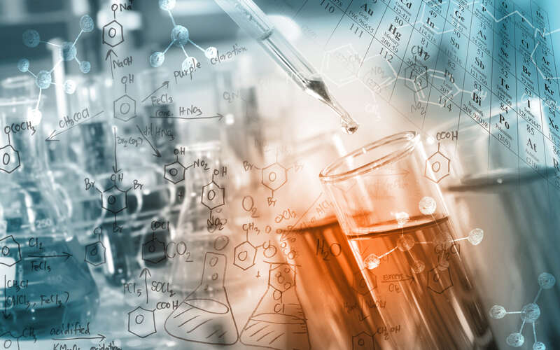 Researcher dropping the clear reagent into test tube with periodic table and chemical equations background, for reaction testing in chemical laboratory.