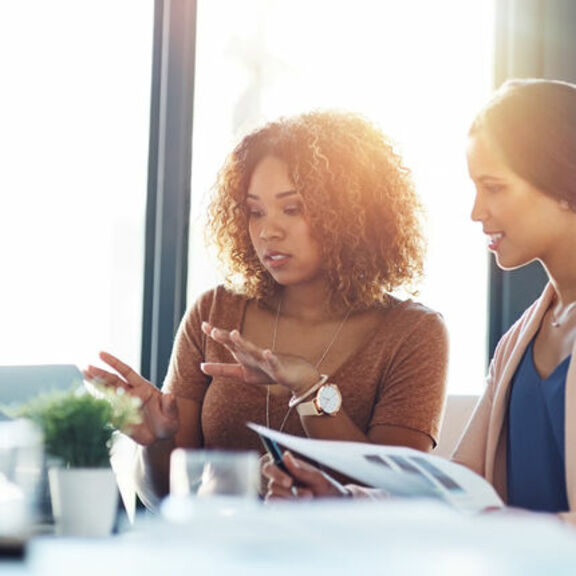 Two women at a desk looking at a laptop